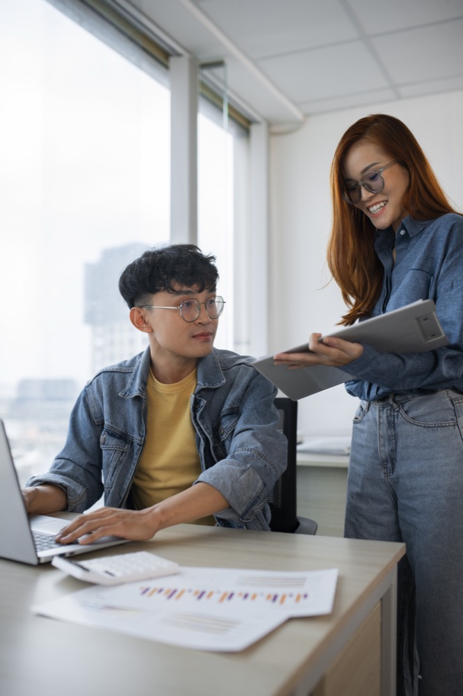 Two colleagues reviewing work together at a desk